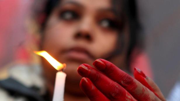 epa03519149 An Indian protester, with hands colored in fake blood, holds a candle during a protest campaign by Youth Congress against the gang rape of a student last week, in Calcutta, India, 28 December 2012. The 23-year-old Indian gang rape victim being treated in a Singapore hospital was in extremely critical condition and struggling to survive, doctors said on 28 December. The woman was raped and beaten in a moving bus in New Delhi on 16 December. The attack triggered protests in the Indian capital and other cities. EPA/PIYAL ADHIKARY