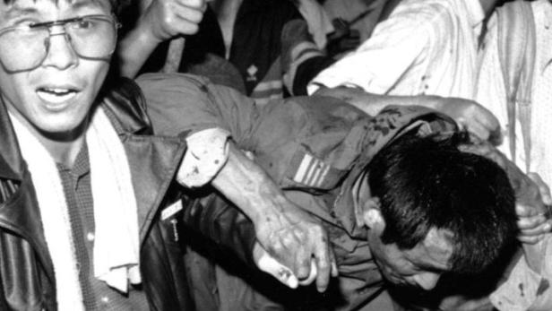 A captured tank driver is helped to safety by students as the crowd beats him during the army crackdown on the pro-democracy movement in Beijing in this June 4, 1989 file photo. Relatives of victims went to Beijing cemeteries on June 4, 2003 to mark the anniversary of the 1989 Tiananmen massacre, laying flowers and bowing to portraits of loved ones under the watchful eyes of police. For many Chinese, interest has faded as they enrich themselves from economic reform, but 14 years after troops and tanks crushed student-led demonstrations on June 3 and 4, the relatives find it hard to forgive and harder to forget. REUTERS/Stringer/Files