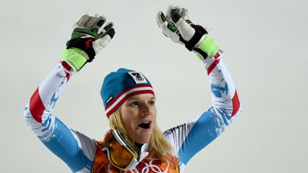 Eine Skirennläuferin jubelt mit erhobenen Armen.