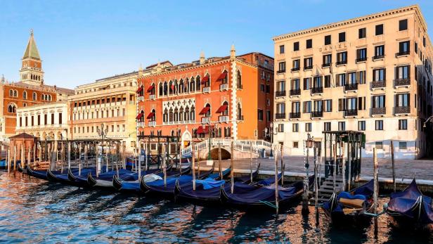 Gondeln liegen am Ufer vor dem Dogenpalast und dem Hotel Danieli in Venedig.
