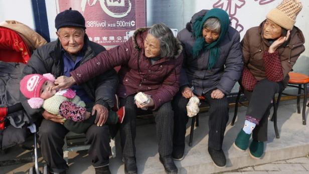 An elderly couple feed their great-grandson with a piece of cake as they sit under the sun in winter in Jiaxing, Zhejiang province, January 9, 2013. China&#039;s one-child policy has produced less trusting, less trustworthy and less competitive children compared to the generation born before the policy was introduced, a study has found. Picture taken January 9, 2013. REUTERS/William Hong (CHINA - Tags: SOCIETY POLITICS FOOD TPX IMAGES OF THE DAY)