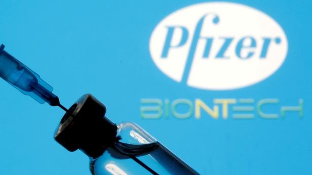 FILE PHOTO: Vial and sryinge are seen in front of displayed Pfizer and Biontech logo