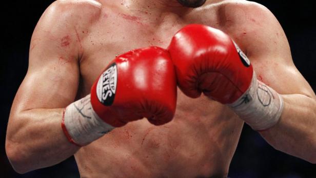 Ein Boxer mit roten Boxhandschuhen und Blutergüssen auf der Haut.