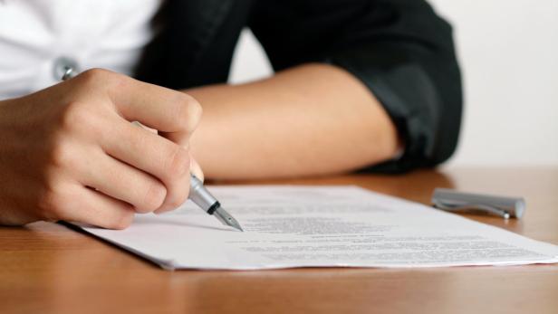 Eine Person unterschreibt ein Dokument mit einem Füllfederhalter.