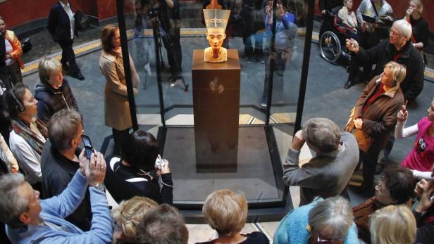 Besucher betrachten die Büste der Nofretete in einem Museum.