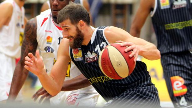 Ein bärtiger Basketballspieler dribbelt den Ball während eines Spiels.