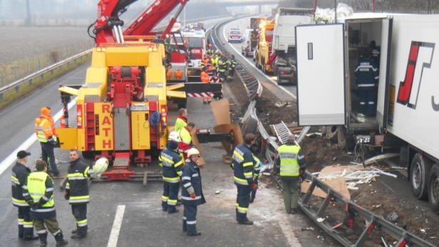 Ein Verkehrsunfall mit mehreren beteiligten Lastwagen auf einer Autobahn, Rettungskräfte sind vor Ort.