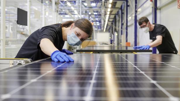 Zwei Arbeiter kontrollieren fertig produzierte Photovoltaikmodule