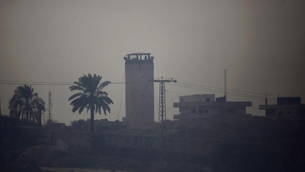 Ein Wachturm und Palmen stehen in einer dunstigen Landschaft.