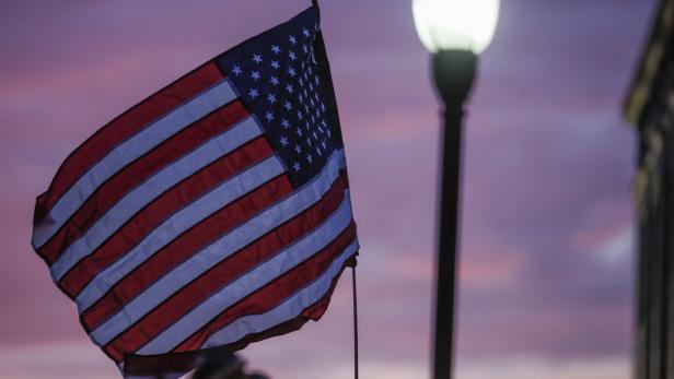 Eine amerikanische Flagge weht vor einem violetten Himmel bei Dämmerung.