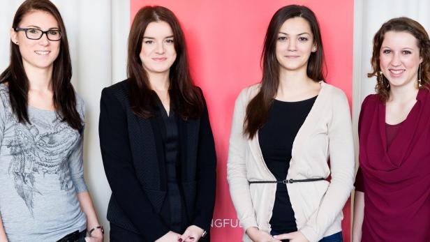 Vier Frauen stehen nebeneinander vor einem roten und weißen Hintergrund.