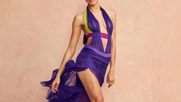 Zendaya posiert in einem lilafarbenen Kleid mit hohem Schlitz und passenden Absätzen.