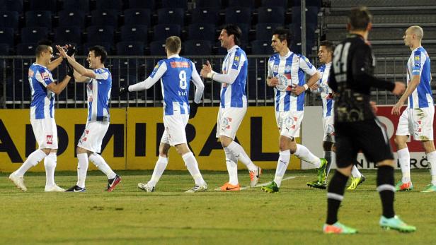Mehrere Fußballspieler in blau-weiß gestreiften Trikots feiern auf dem Spielfeld.
