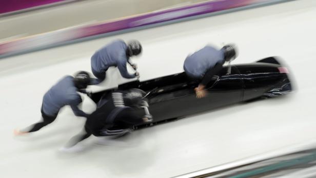 Ein Viererbob rast mit hoher Geschwindigkeit durch eine Eisrinne.