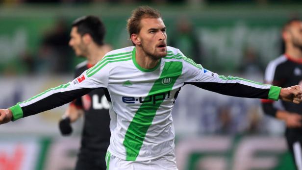 Ein Fußballspieler im Trikot des VfL Wolfsburg jubelt mit geballten Fäusten.