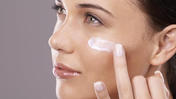 Eine Frau trägt Feuchtigkeitscreme auf ihr Gesicht auf.