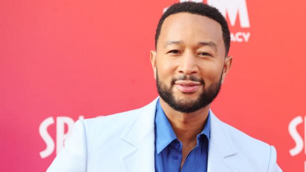 Ein Porträt von John Legend vor einem roten Hintergrund.