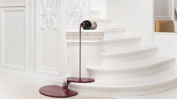 Eine Weinflasche liegt auf einer Treppe, aus der eine rote Flüssigkeit fließt.