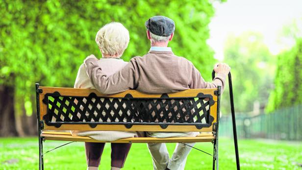 Senior couple sitting on a wooden bench in the park