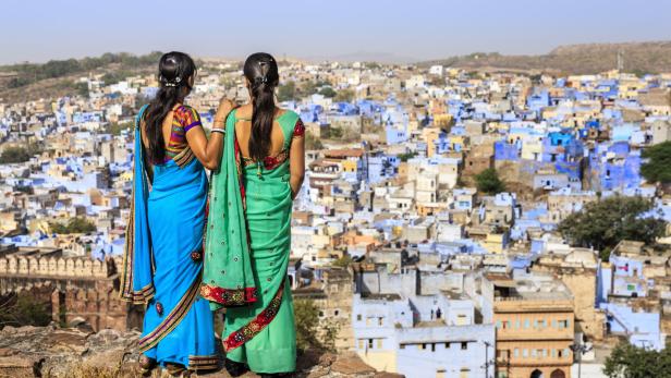 Zwei Frauen in Saris blicken auf die blaue Stadt Jodhpur, Indien.