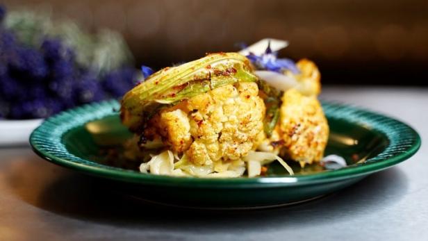 Ein Teller mit gebratenem Blumenkohl, garniert mit essbaren Blüten.