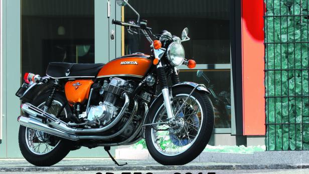 Eine orangefarbene Honda CB750 Four steht vor einem Gebäude.