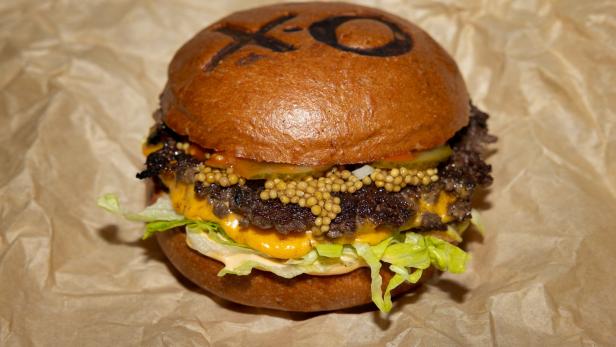 Ein Burger mit Salat, Käse, Senf und einem „XO“-Muster auf dem Brötchen.