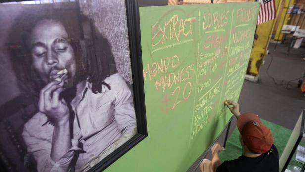 Ein Porträt von Bob Marley hängt neben einer Tafel mit einer Preisliste für Cannabisprodukte.