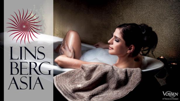 Eine Frau entspannt in einer Badewanne mit Schaum, ein Handtuch liegt bereit.