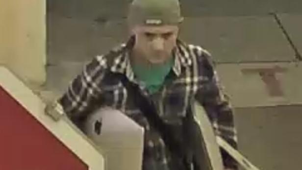 Ein Mann mit Mütze und kariertem Hemd geht durch eine Drehkreuzanlage.