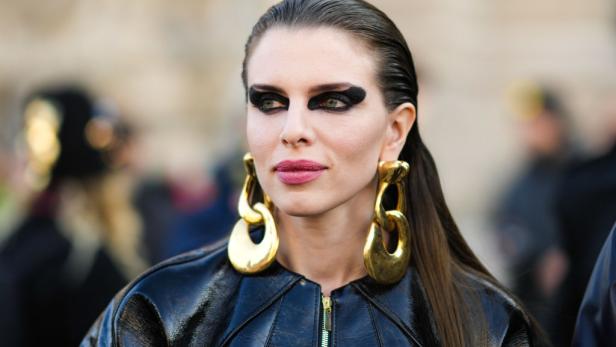 Eine Frau mit starkem, schwarzem Augen-Make-up und großen, goldenen Ohrringen.