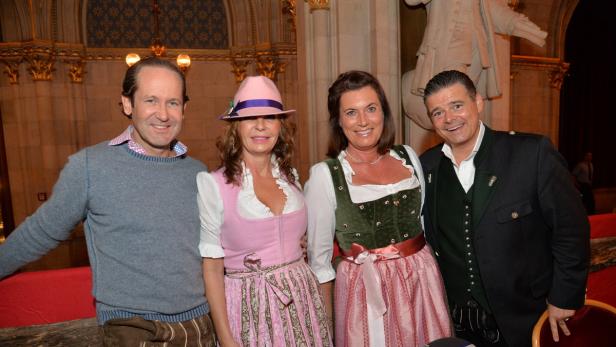 Vier Personen in Tracht posieren für ein Foto in einem eleganten Gebäude.