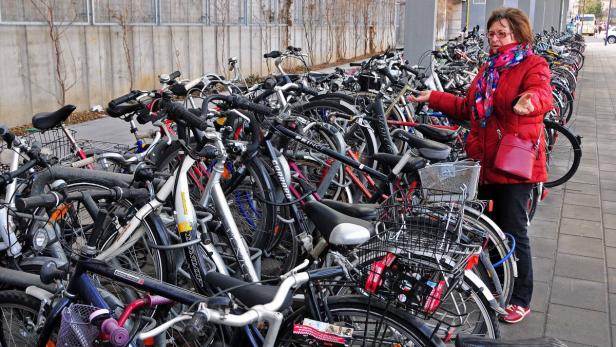 Eine Frau steht vor einem Fahrradständer voller Fahrräder.