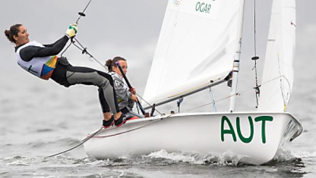 Zwei Seglerinnen steuern ein Segelboot mit der Aufschrift „AUT“ auf dem Wasser.