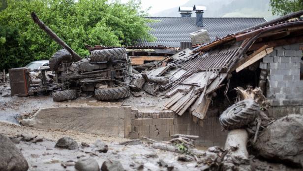 Ein umgestürzter Traktor und ein beschädigtes Haus nach einer Schlammlawine.