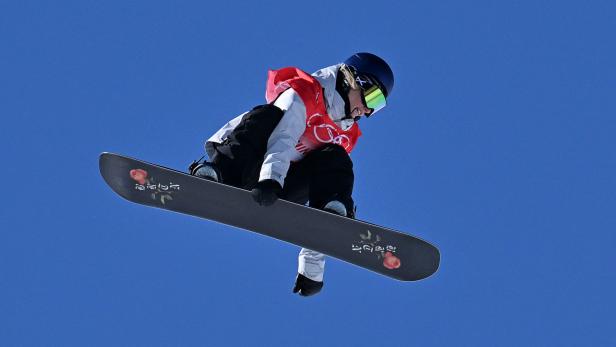 Eine Snowboarderin springt vor blauem Himmel bei den Olympischen Spielen 2022 in Peking.