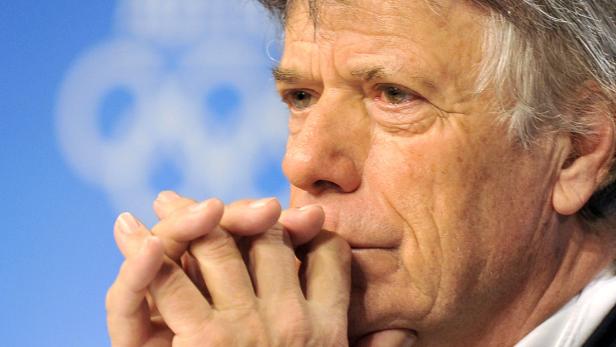 Nahaufnahme eines Mannes mit den Händen vor dem Mund, der nachdenklich wirkt.