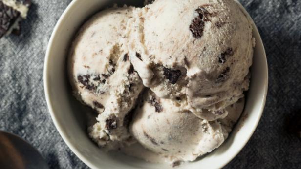 Eine Schüssel mit cremigem Eis mit Keksstückchen steht auf einem Tisch.