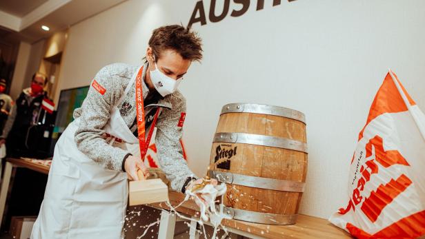 Ein Mann im Österreich-Outfit schlägt ein Bierfass der Marke Stiegl an.