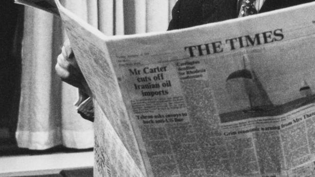 Eine Person liest die Zeitung „The Times“ mit der Schlagzeile „Mr. Carter stoppt iranische Ölimporte“.