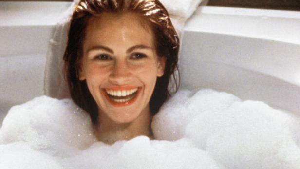 Julia Roberts liegt lächelnd in einer mit Schaum bedeckten Badewanne.