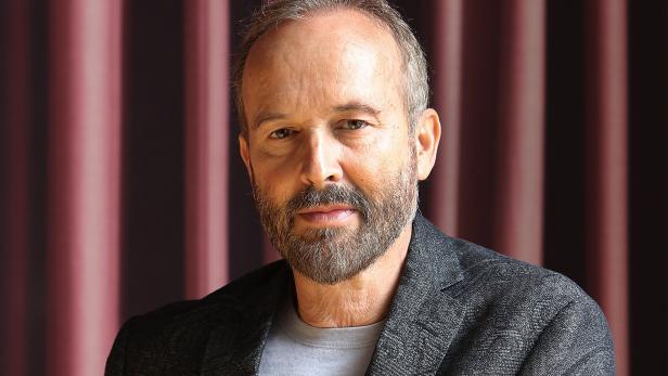 Ein Mann mit Bart lehnt an einem Geländer.