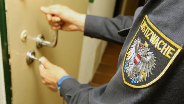 Ein Justizwachebeamter schließt eine Tür auf.