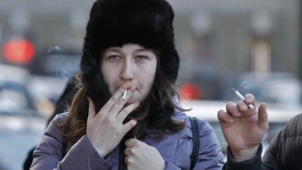 People smoke in a street in St. Petersburg January 24, 2013. Russian lawmakers on Friday backed a law which would ban smoking in bars, cafes and other public spaces to promote healthier living in the world&#039;s largest tobacco market after China. Supported by President Vladimir Putin, who likes to present a healthy, active image, and has previously rebuked ministers for smoking, the bill was voted through in a second reading in the State Duma, the lower house of parliament. Picture taken January 24, 2013. REUTERS/Alexander Demianchuk (RUSSIA - Tags: POLITICS BUSINESS HEALTH)