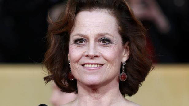 Porträt von Sigourney Weaver mit roten Ohrringen und lockigem Haar.
