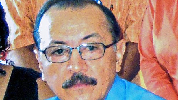 Ein Mann mit Brille und Schnurrbart trägt ein blaues Hemd.