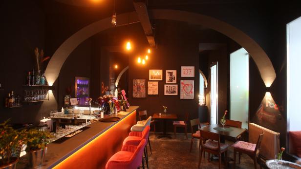 Innenansicht einer Bar mit dunkler Einrichtung und beleuchteter Theke.