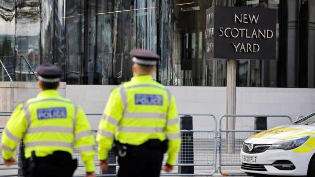 Zwei Polizisten gehen vor dem New Scotland Yard Gebäude entlang.