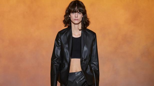 Eine Frau in einem schwarzen Lederanzug auf einem Laufsteg.