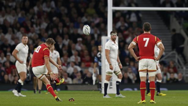 Ein Rugby-Spieler tritt den Ball vor einem Publikum.